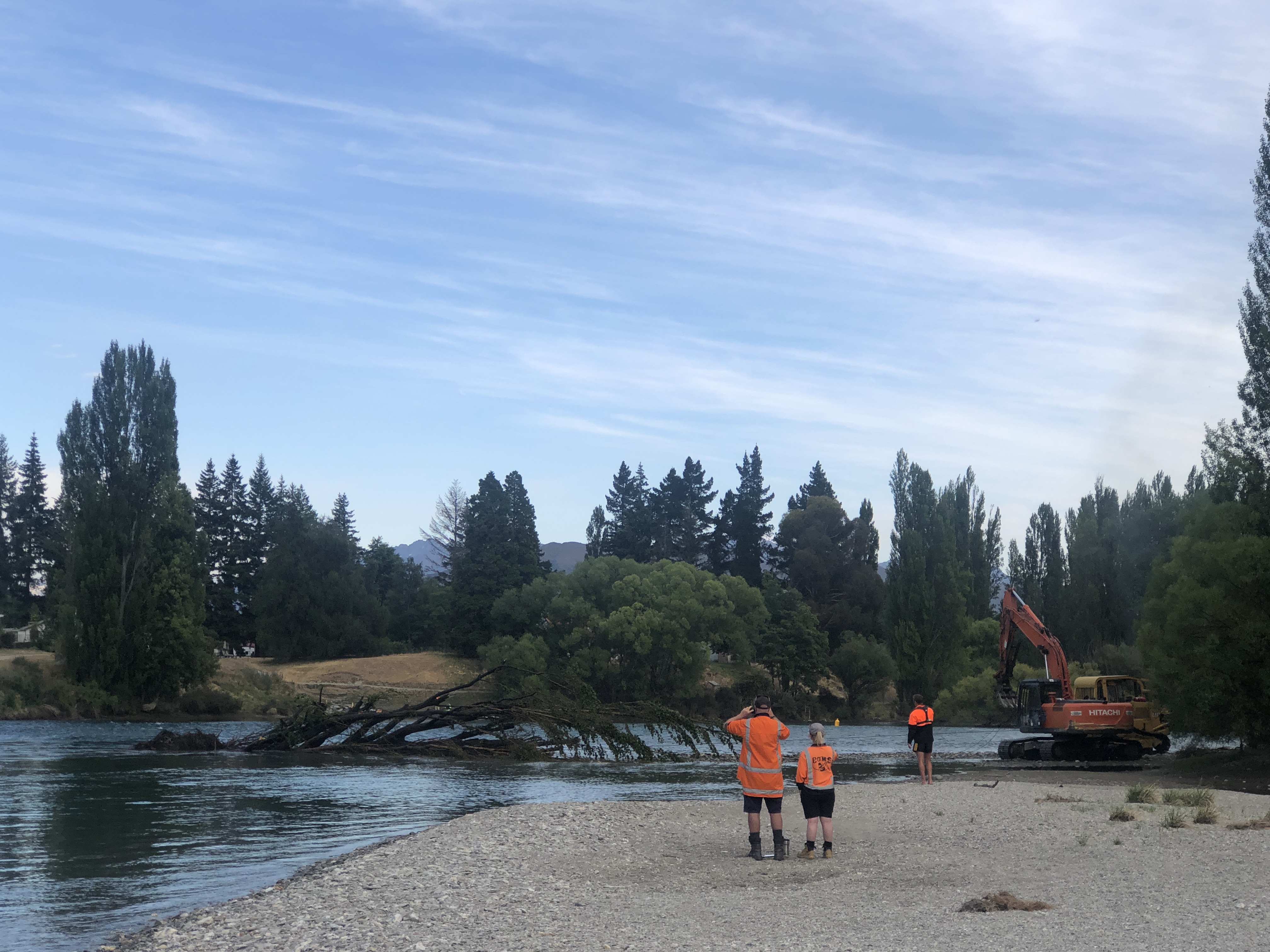 Staff monitor the tree as it nears the far riverbank, winched by an excavator.