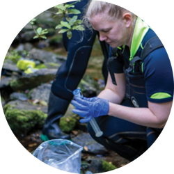 Photograph of scientist wearing gloves testing water samples at river